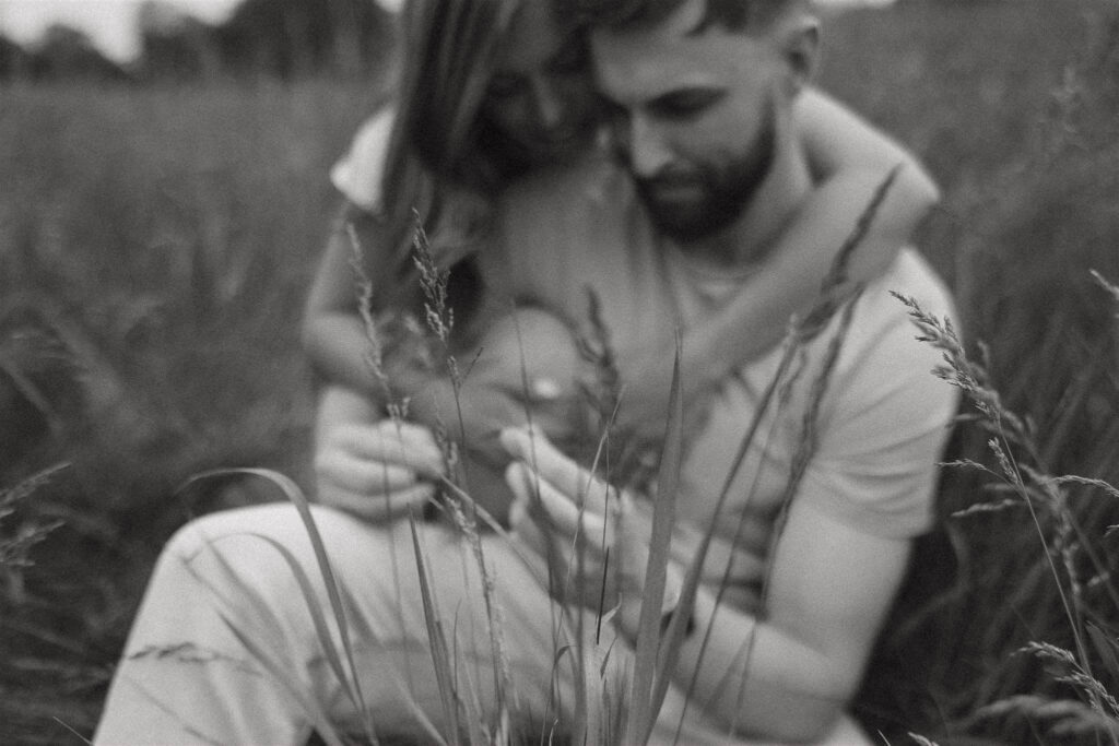 Engaged couple looks at flowers together in romantic engagement photos