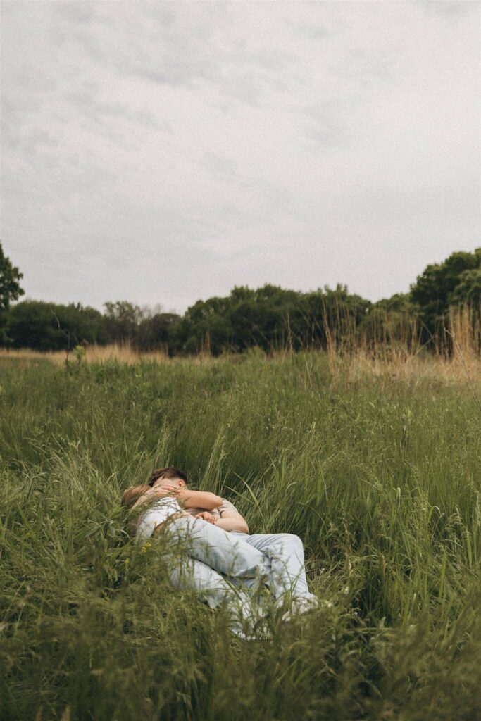 Couple lies in the meadow grass in Minnesota engagement photos