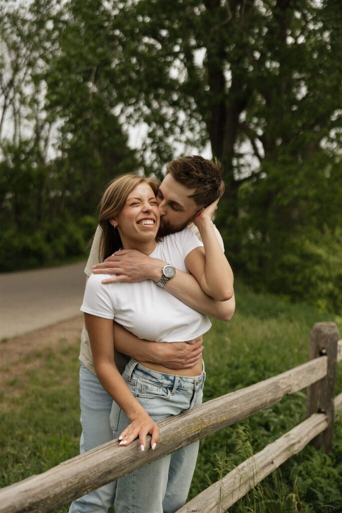 Man embraces woman from behind in Minnesota engagement photos