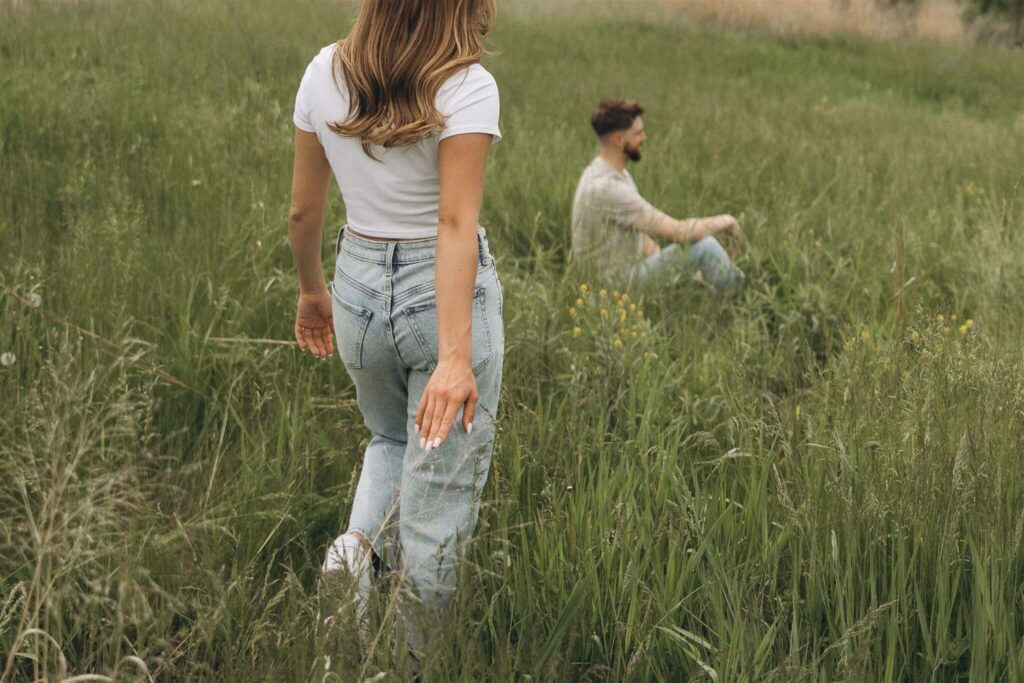 Woman walks towards her fiance as her fingertips graze the meadow grass