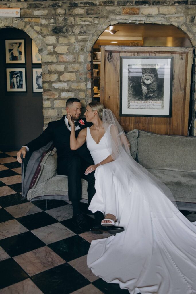 Bride and groom sit on couch at sophisticated microwedding venue with black and white tile floors