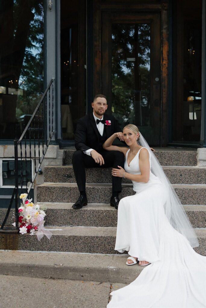 Bride and groom sit on steps outside Bar Lurcat in downtown Minneapolis