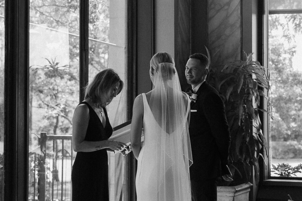 Groom steals a glance at bride during their microwedding ceremony