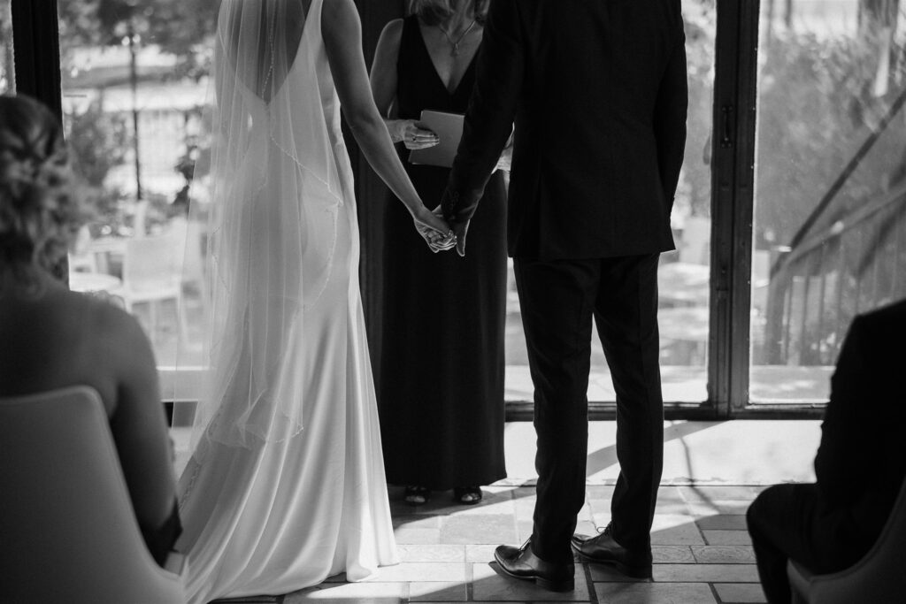 Bride and groom holds hands during microwedding ceremony