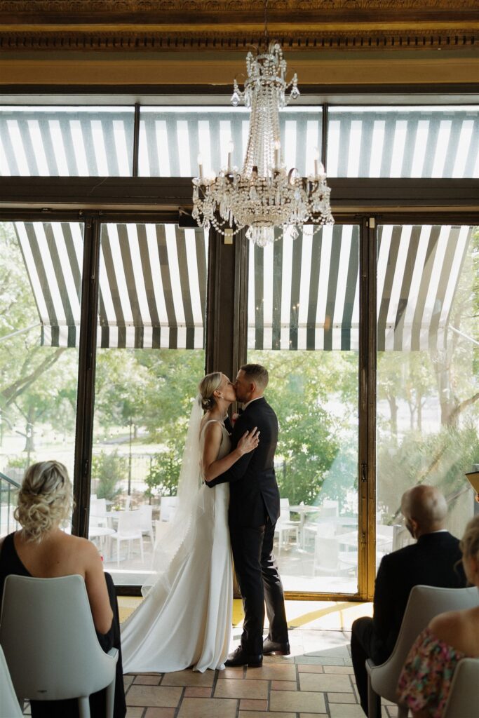 Newlyweds kiss under chandelier at Bar Lurcat in downtown Minneapolis