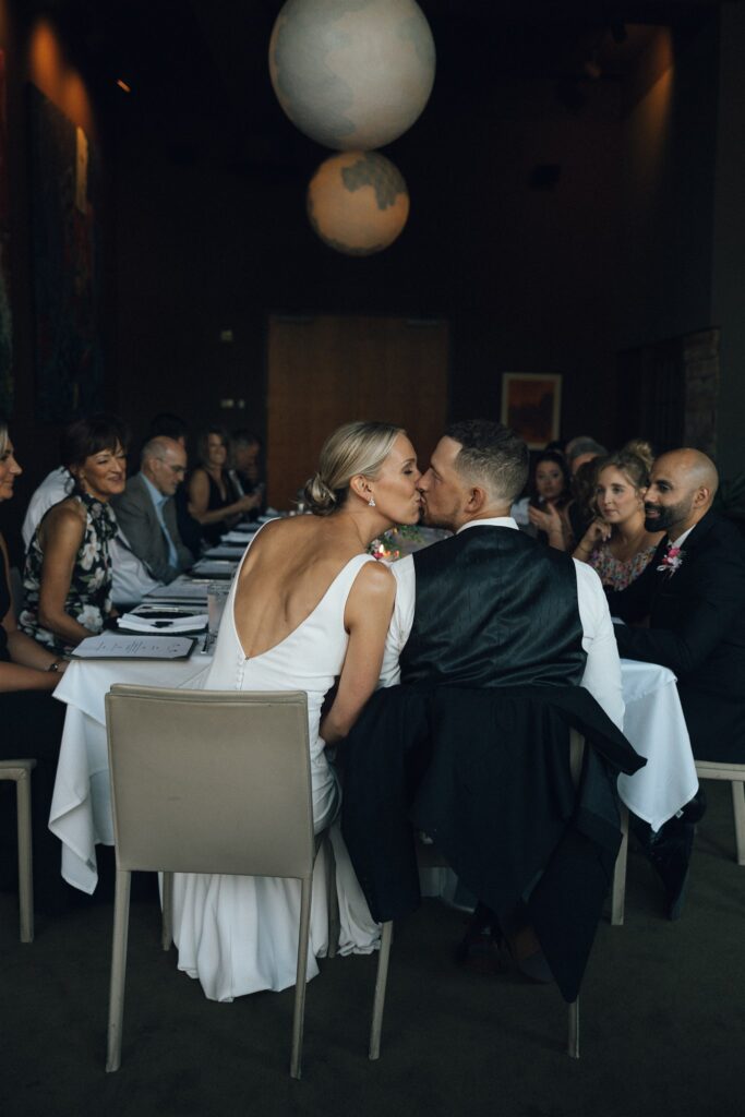 Bride and groom kiss at harvest table microwedding reception at Bar Lurcat in downtown Minneapolis