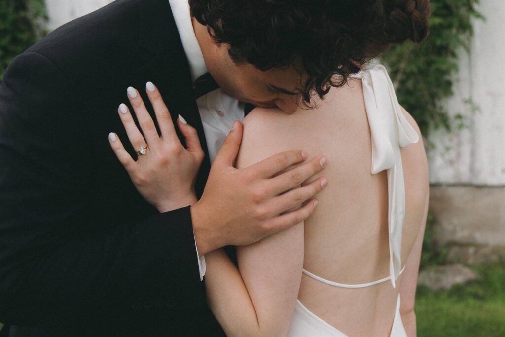 Groom kisses bride's bare shoulder