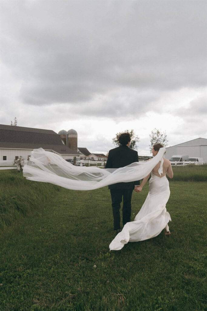 Bride's cathedral veil whips in the wind as her and her husband walk towards Abella wedding venue