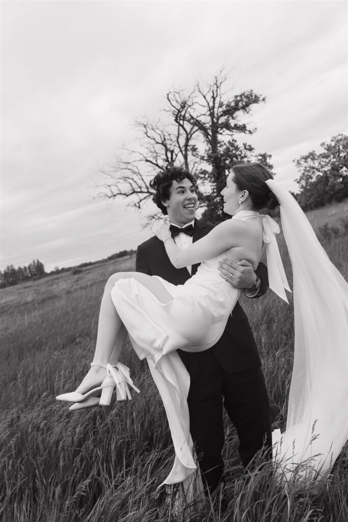 Groom carries bride through stormy meadow in Minnesota