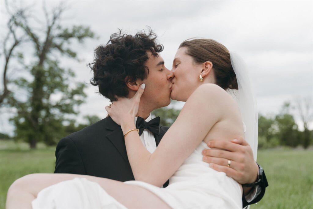 Bride and groom kiss as groom holds her in his arms