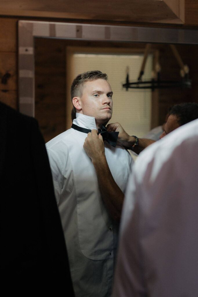 Groom's mother helps him put his bowtie on