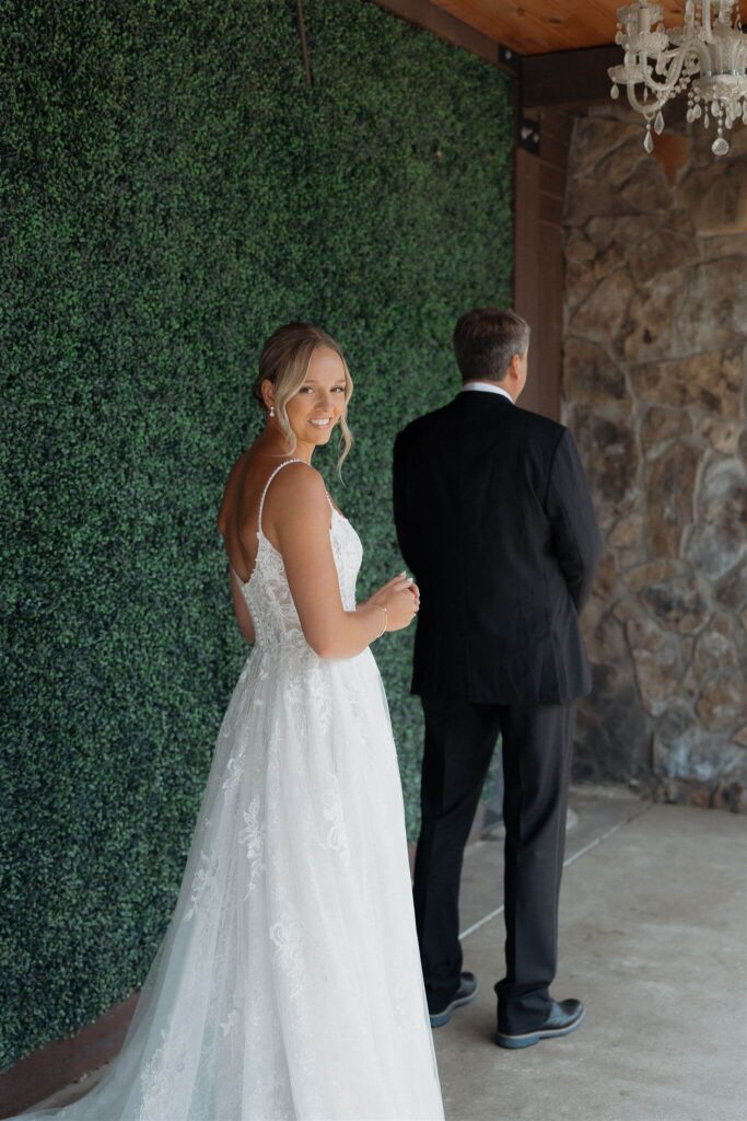 Bride looks over her shoulder as her father waits patiently for his first look