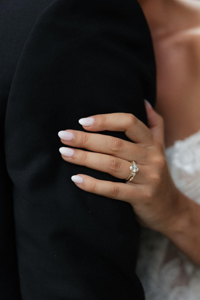 Bride's hand clasps tightly to her husband's arm