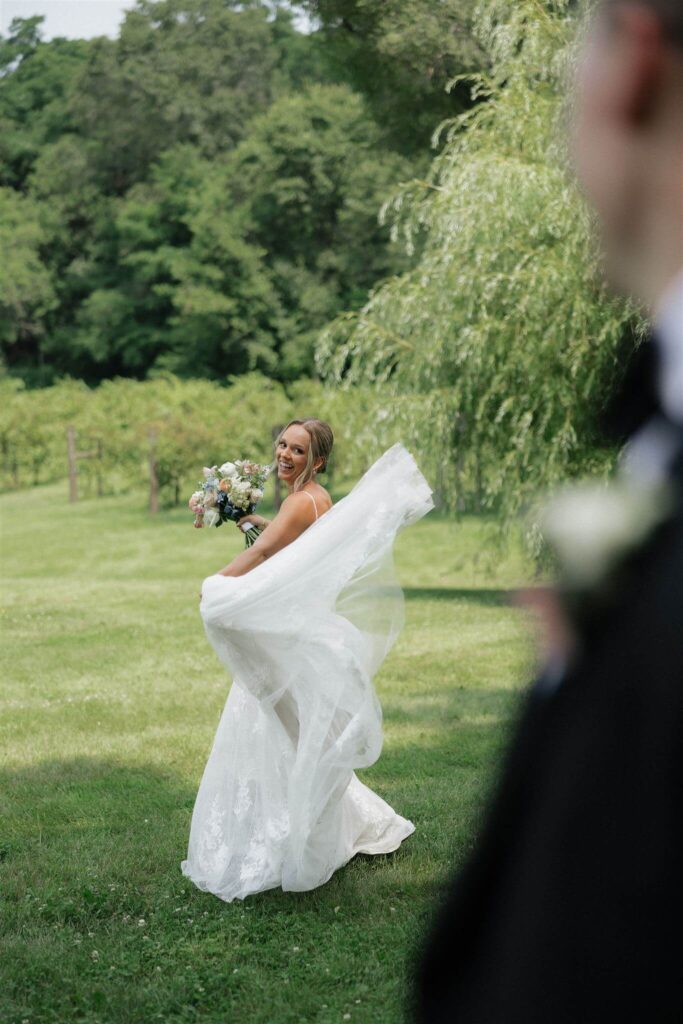 Bride twirls around in her wedding dress while groom looks on at Hope Glen Farm wedding venue