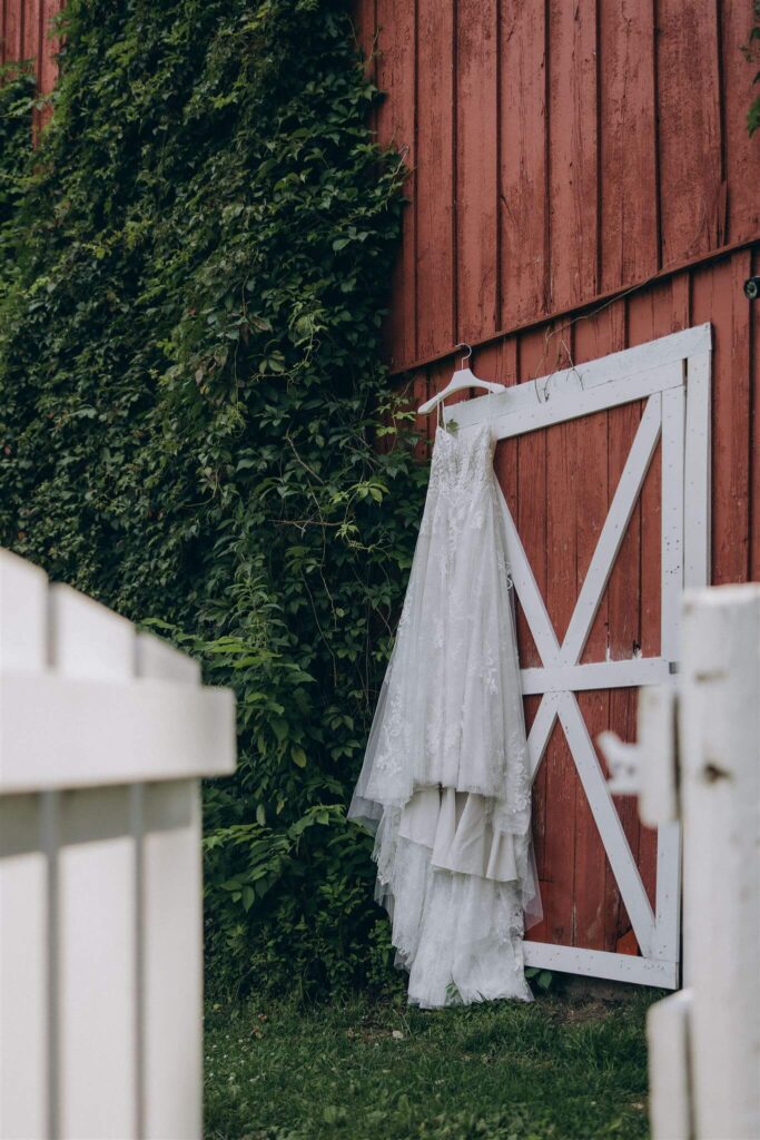 Bride's dress hangs on barn door at luxury farm wedding venue in the Twin Cities