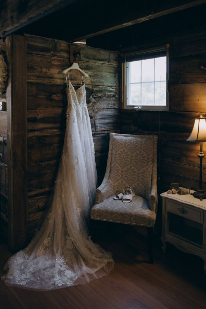 Bride's dress hangs in corner of farm wedding venue