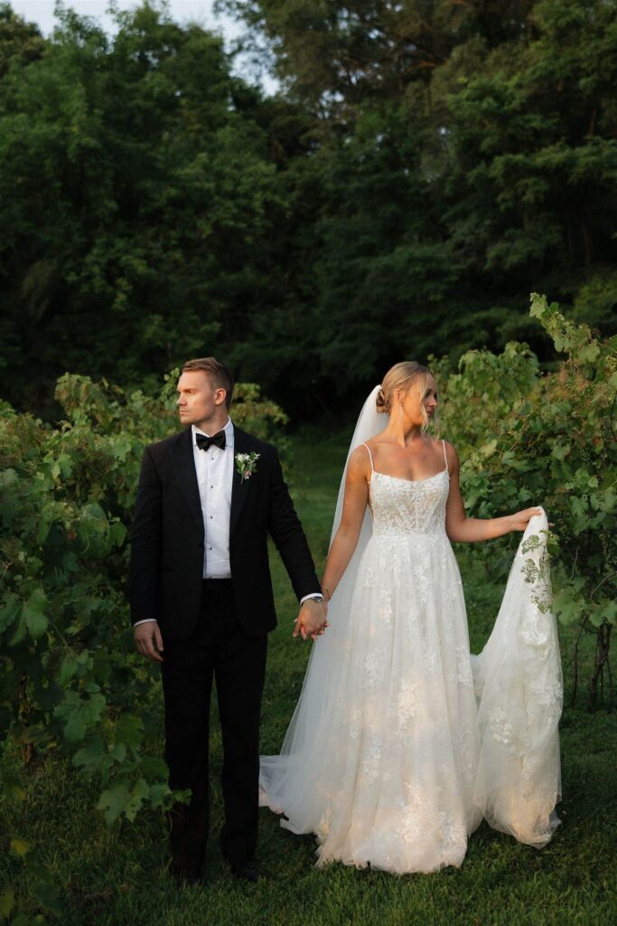 Bride and groom hold hands in vineyard at Hope Glen Farm wedding venue in Minnesota