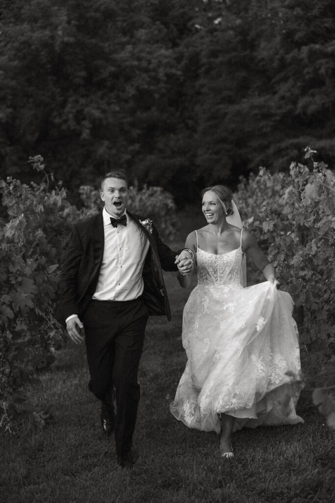 Bride and groom run through vineyard