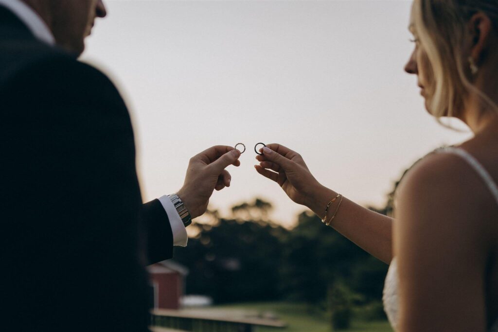 Bride and groom holding wedding bands up to the sky at farm wedding venue in Minnesota