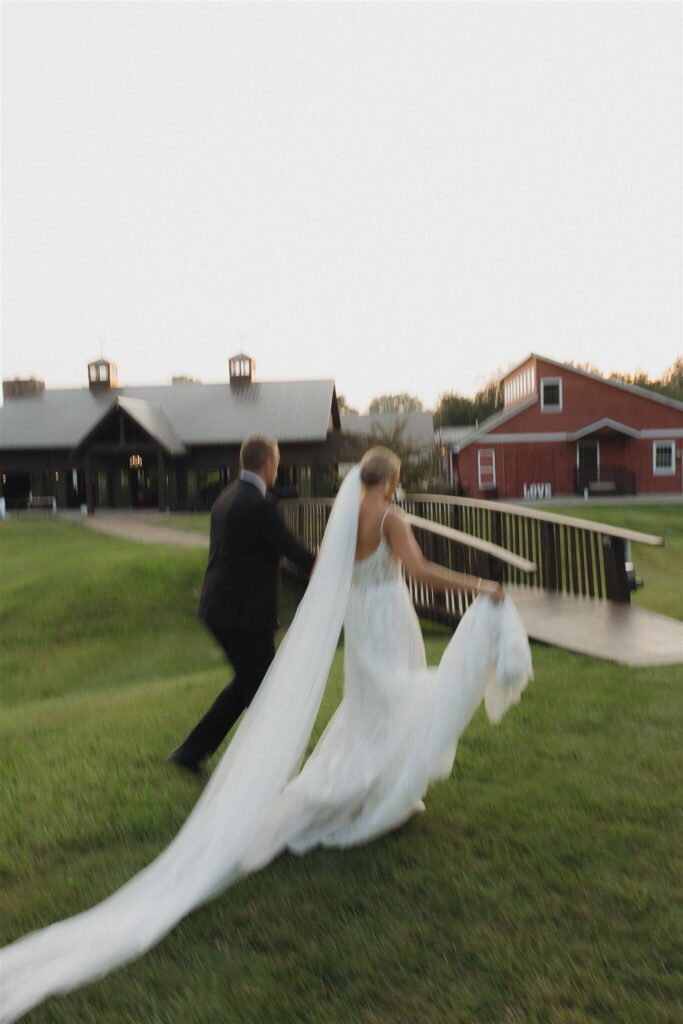 Bride and groom run towards bridge at Hope Glen Farm in Minnesota