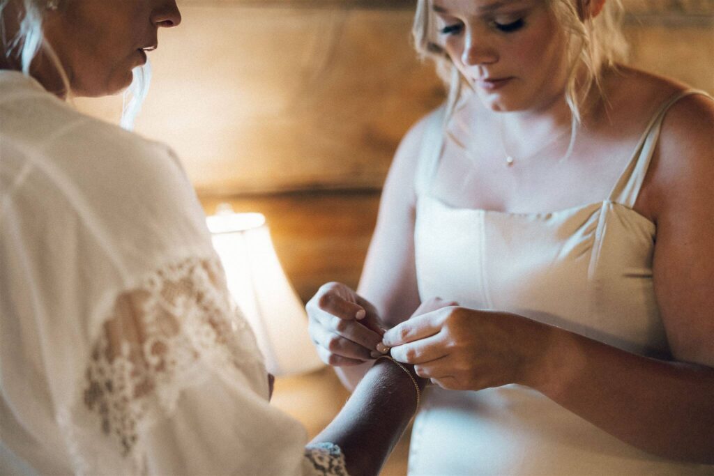 Bride's sister clasps her jewelry around her wrist