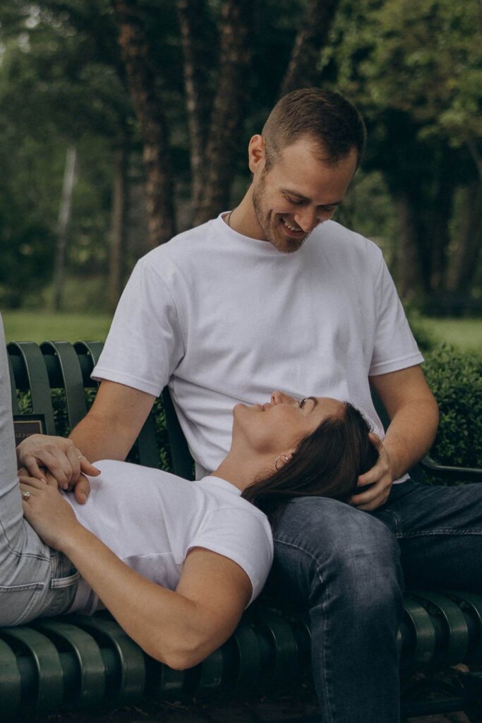 Man looks down at his wife-to-be as her head lays in his lap during St. Paul engagement photo shoot