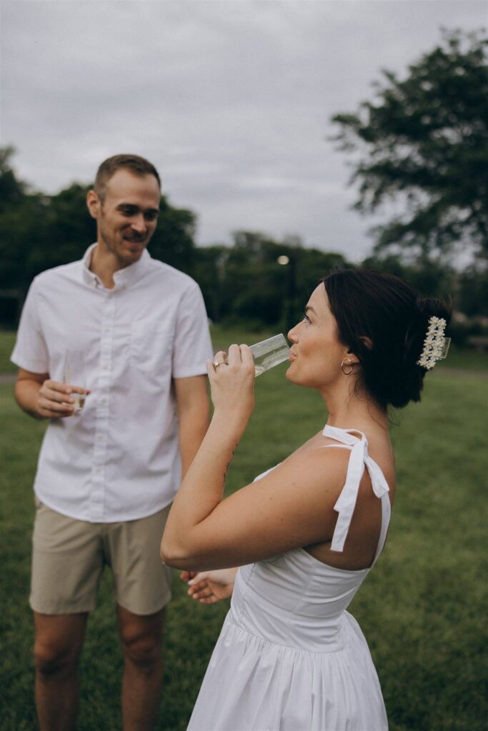 Man and woman take sips of their celebratory champagne during engagement photo shoot