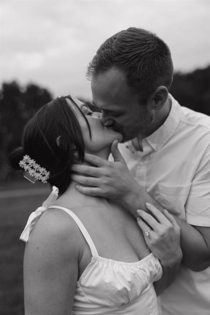 Man kisses his fiance while tenderly grazing her neck with his hand