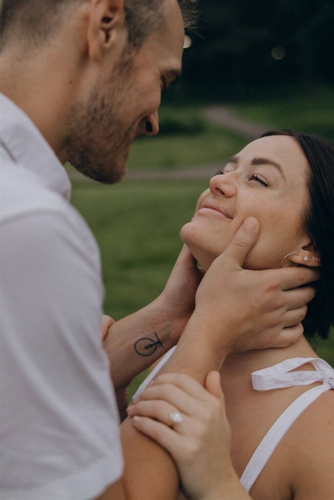 Man cups smiling woman's head in his hands during their engagement photo shoot