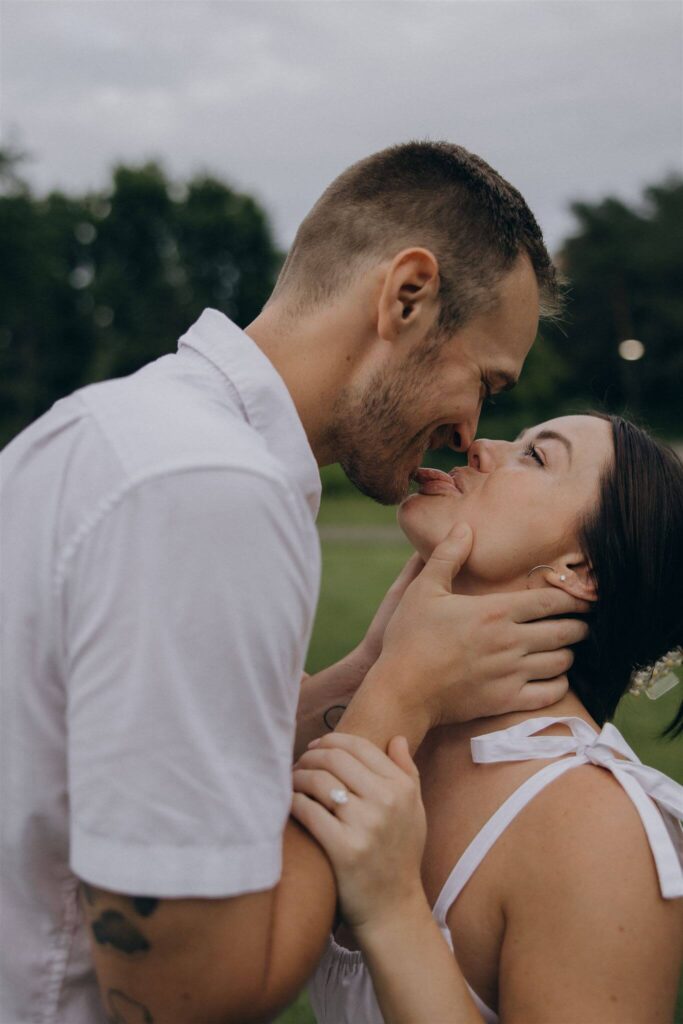 Woman sticks out at her tongue at her fiance as he leans in for a kiss