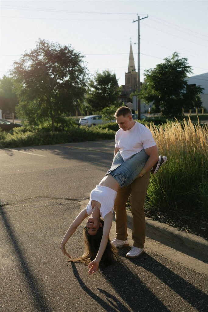 Man holds onto woman as she does acrobatics in Trader Joe's parking lot