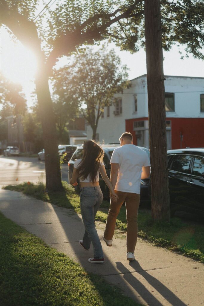 Engaged couple skips down the sidewalk in Northeast Minneapolis engagement photos