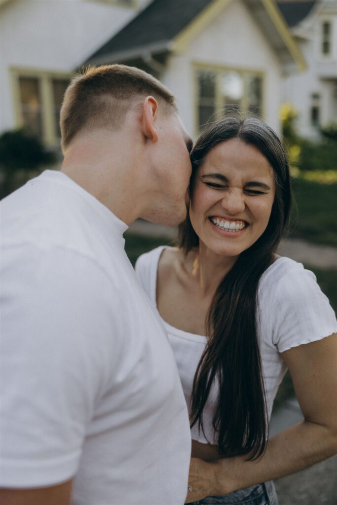 Man kisses woman's cheek as she grins ear to ear