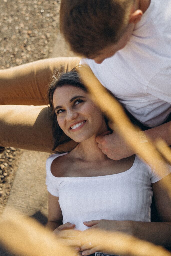 Woman looks up at her fiance as she lays her head in his lap