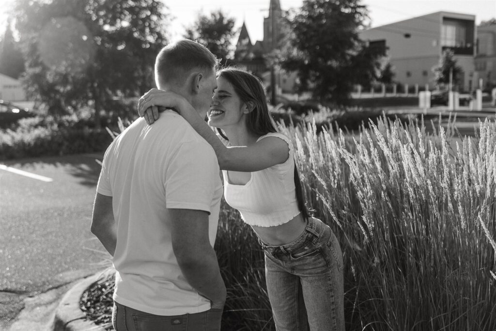 Woman leans in for a kiss as she stands on curb in engagement photos