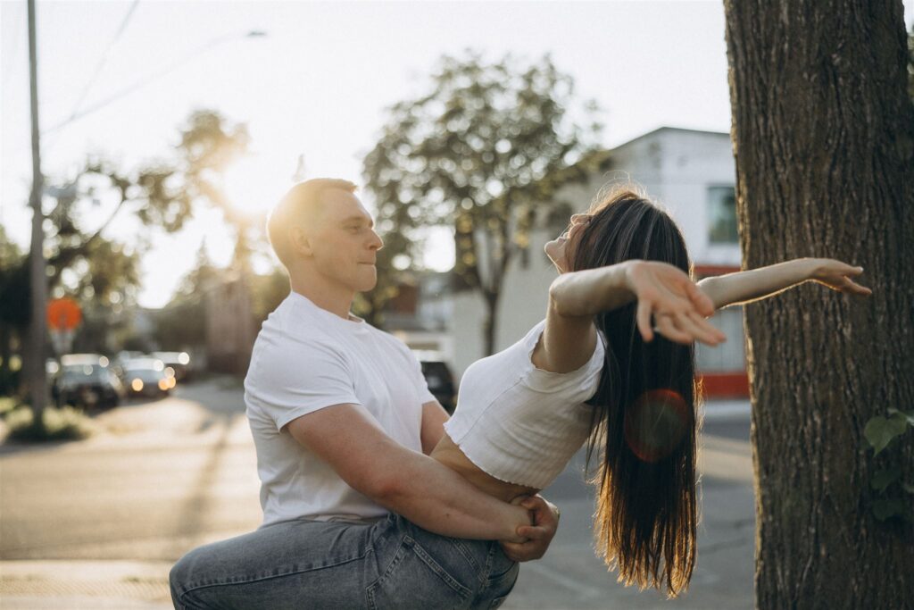 Man twirls his fiance as she throws her hands up in the air