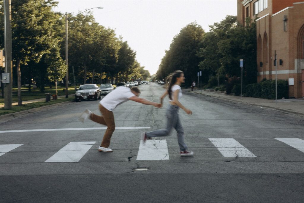 Engaged couple runs across pedestrian crossing