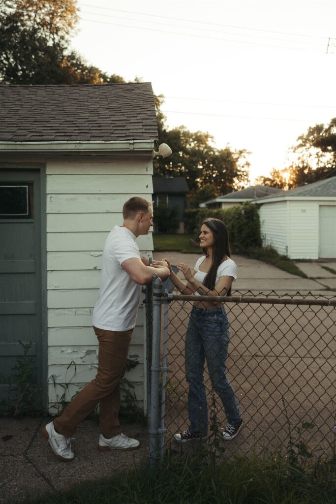 Engaged couple greets each other over their backyard fence