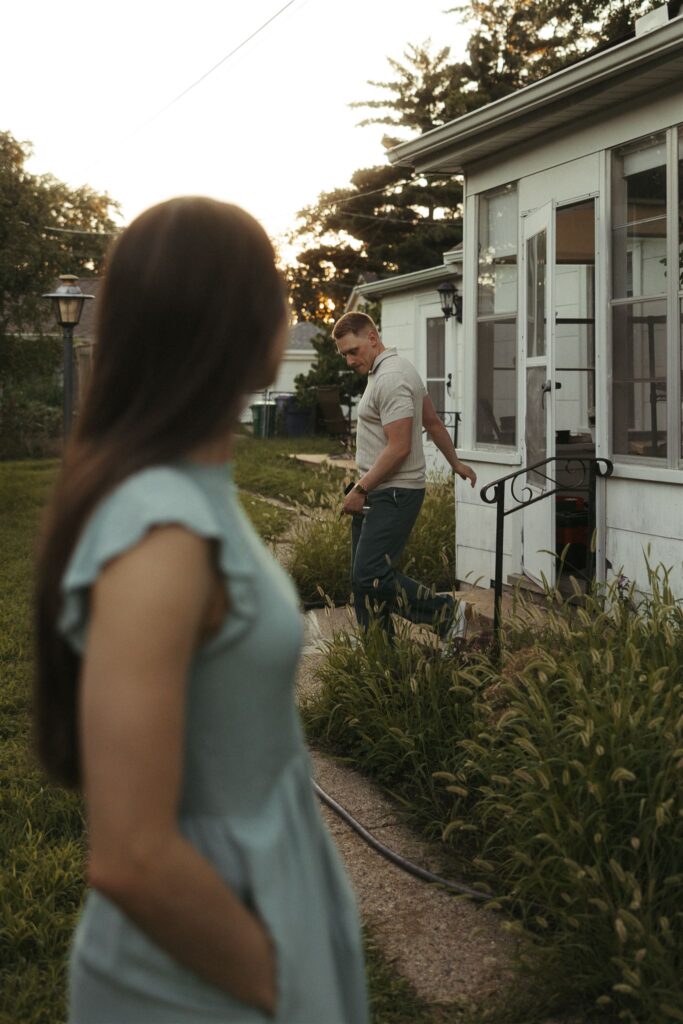 Woman looks behind her as her fiance walks down patio steps of their home