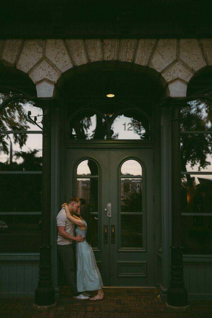 Engaged couple kisses in emerald green doorway of downtown Minneapolis