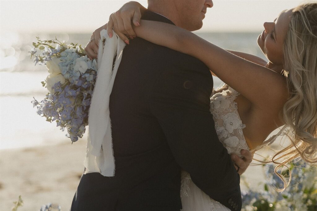 Bride holds bridal bouquet as groom twirls her around in first dance