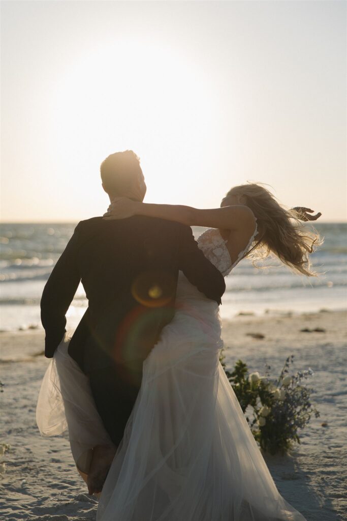 Groom twirls bride in destination elopement as the sun begins its descent behind them