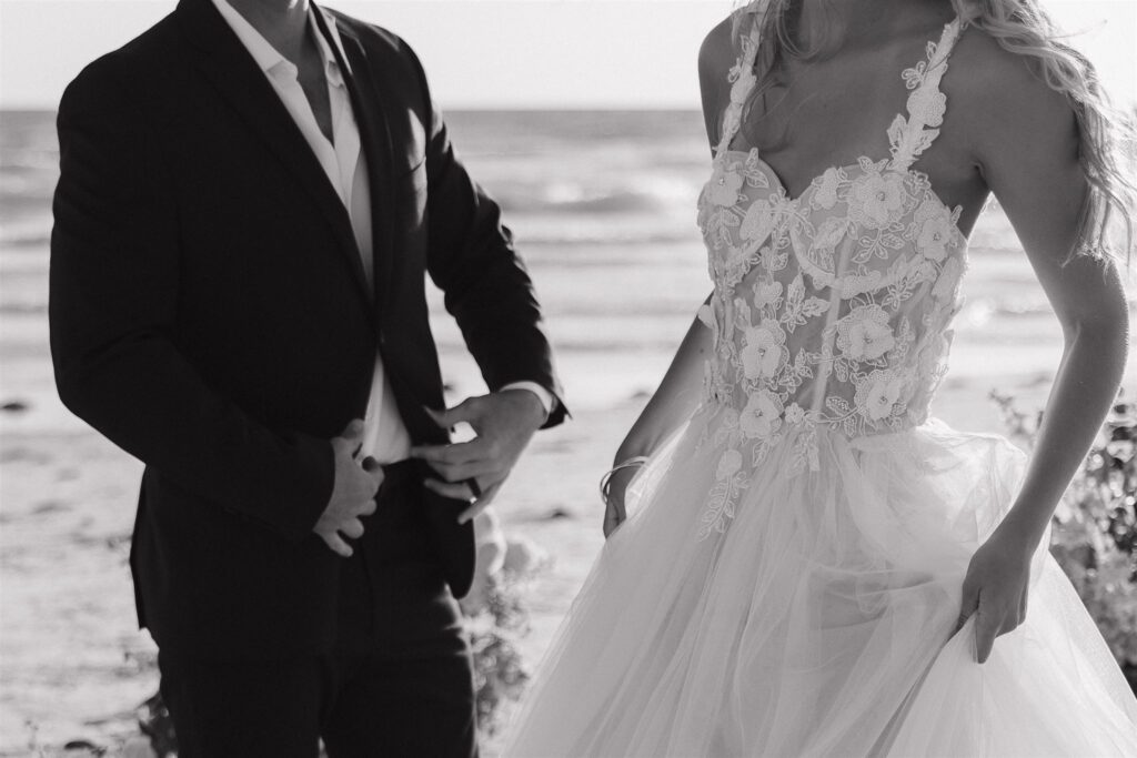 Groom fixes suit and bride holds dress up in destination elopement