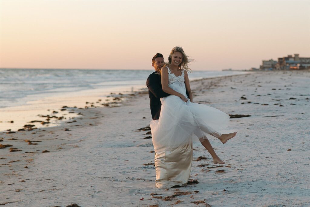 Bride and groom play in the sand at sunset destination elopement