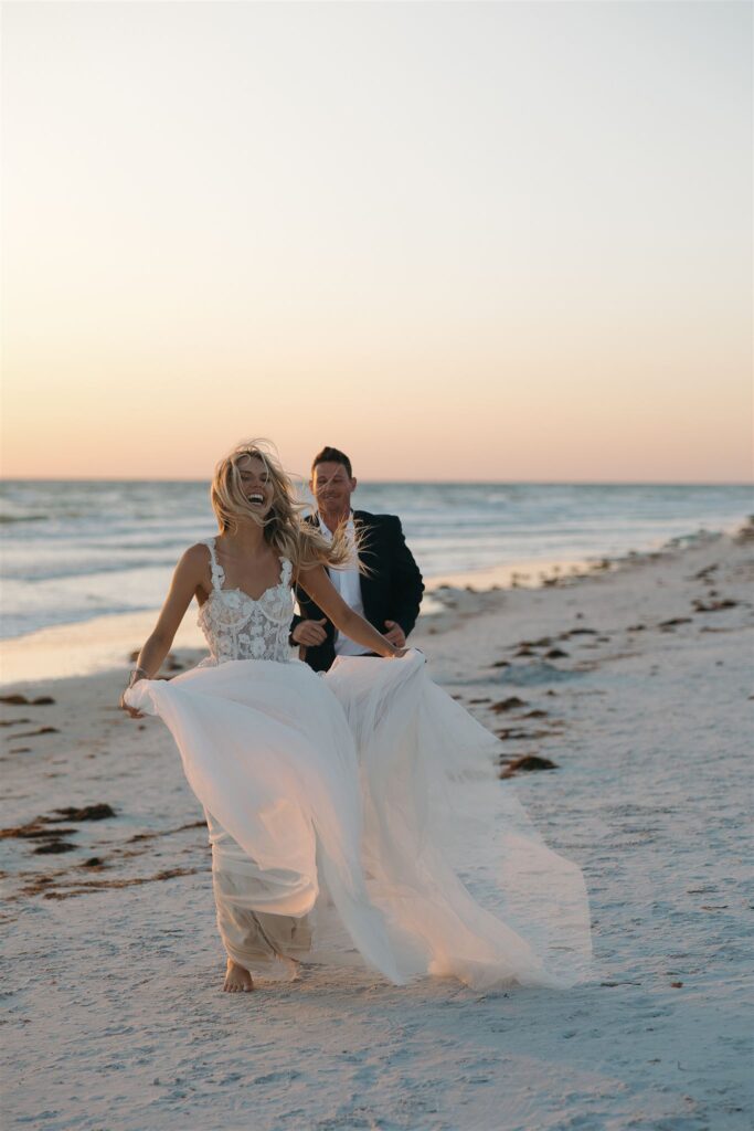 Newlyweds run through the sand in beach destination elopement