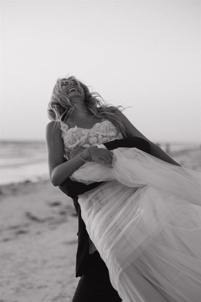 Groom lifts joyful bride into the air during destination elopement