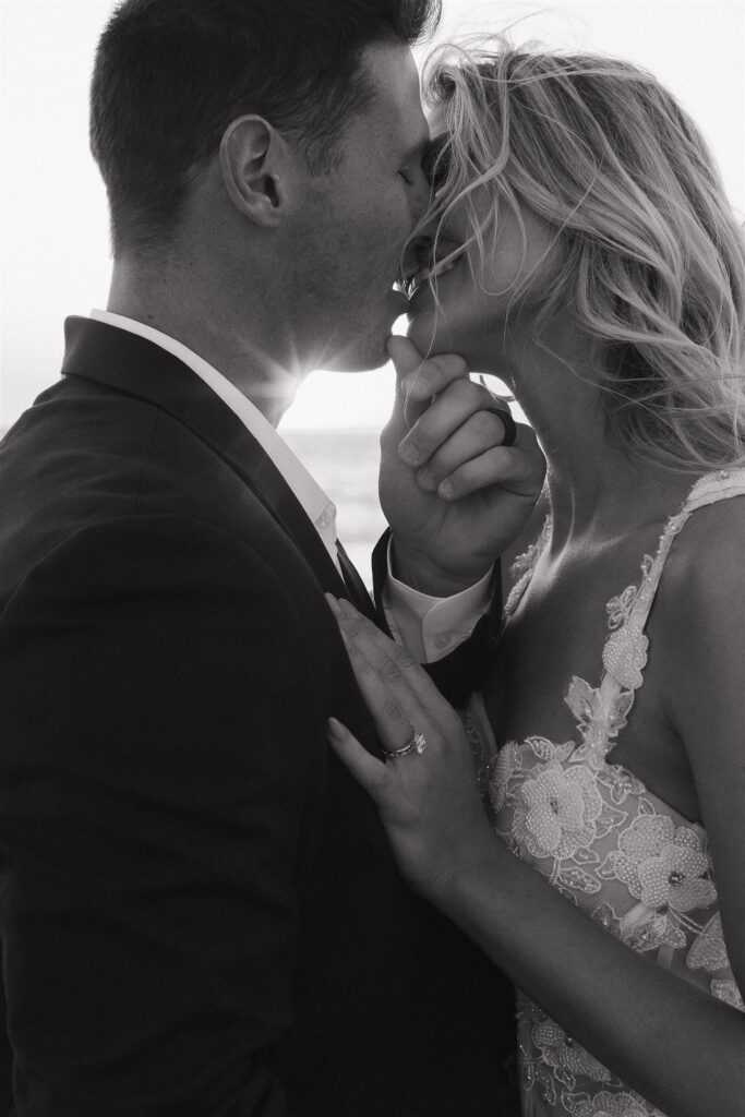 Newlyweds kiss while sun shines through their silhouettes