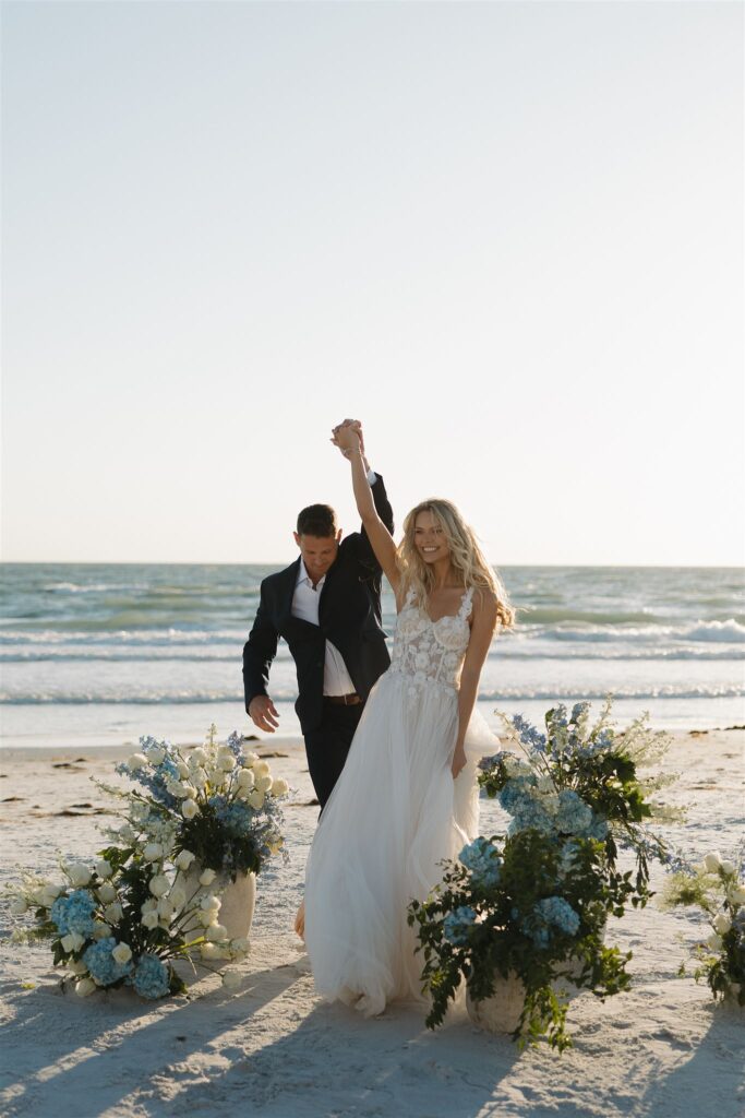 Bride and groom lift their clasped hands in the air as they celebrate having said their 'I do's'