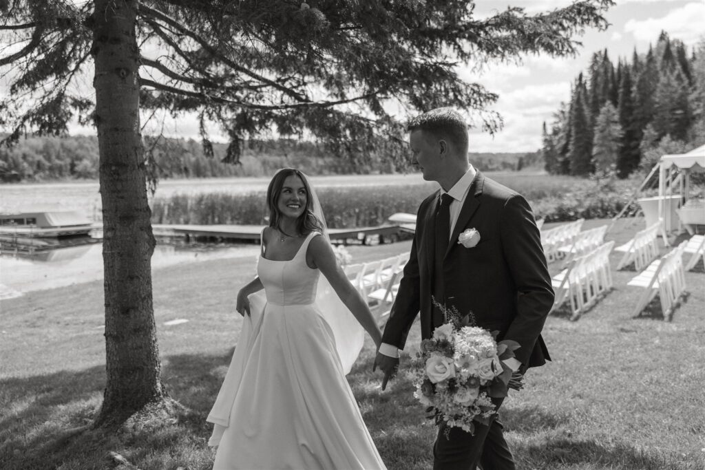 Newlyweds walk hand in hand thorough the lawn of their cabin