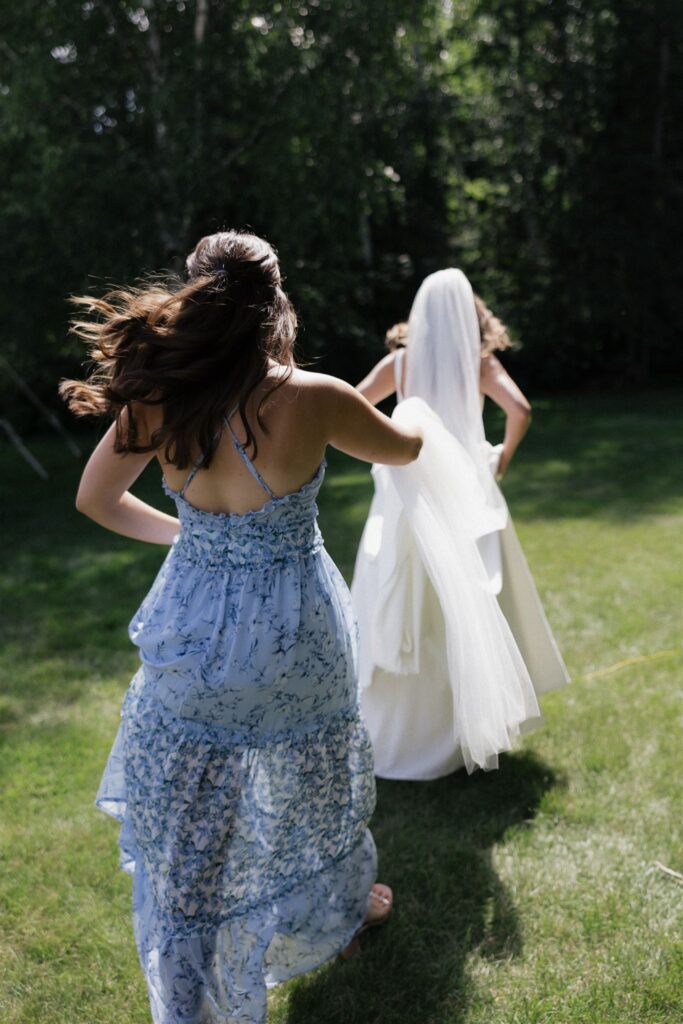 Maid of honor holds onto bride's train as she jogs to her wedding